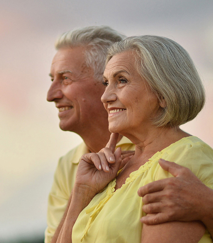 senior couple smiling and looking at a sunset