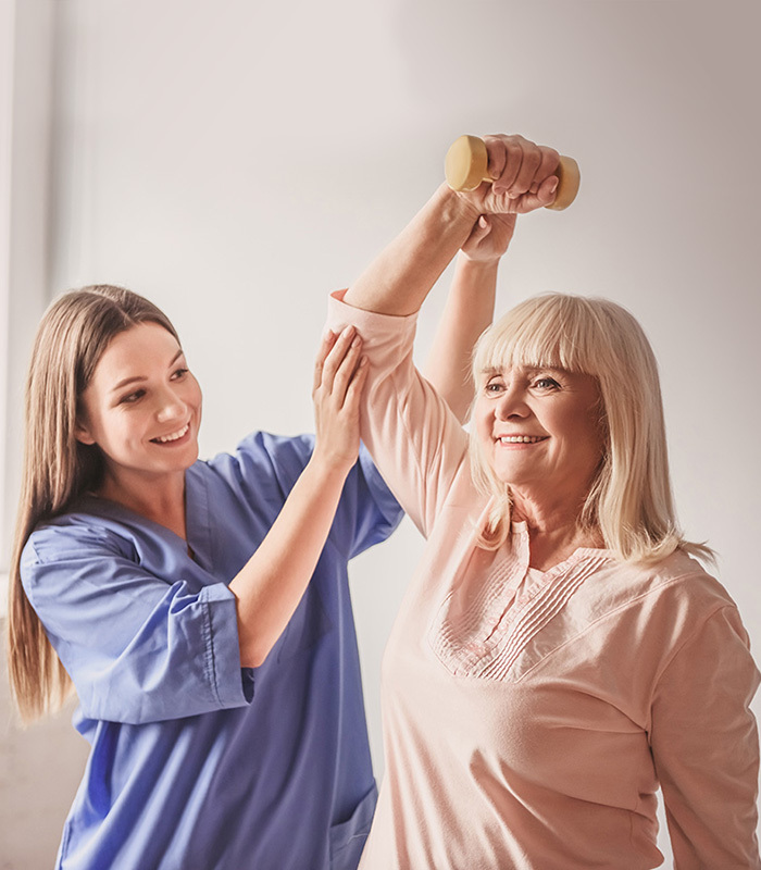 Woman helping senior woman lift up arm with weights